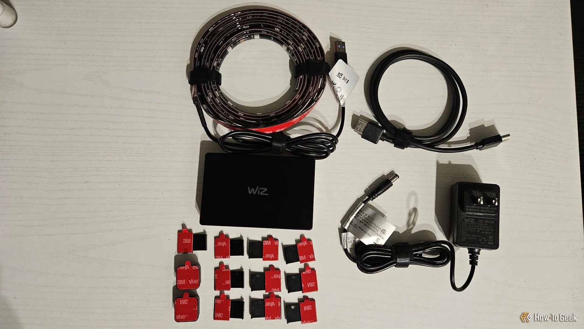 Các thành phần của WiZ HDMI Sync Box và đèn nền TV, bao gồm hộp điều khiển, dây cáp và dải đèn LED.
