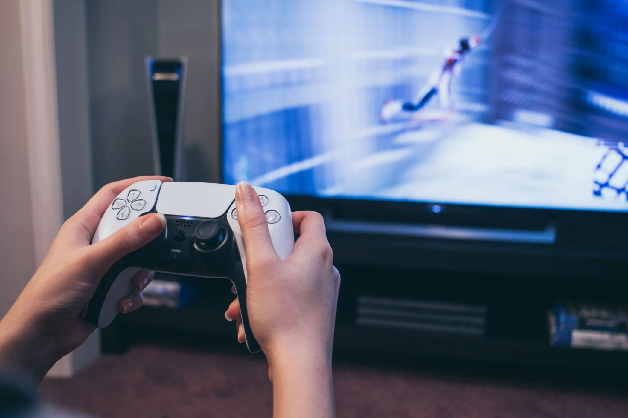 Cầm tay cầm DualSense PS5 trước TV hiển thị Spider-Man