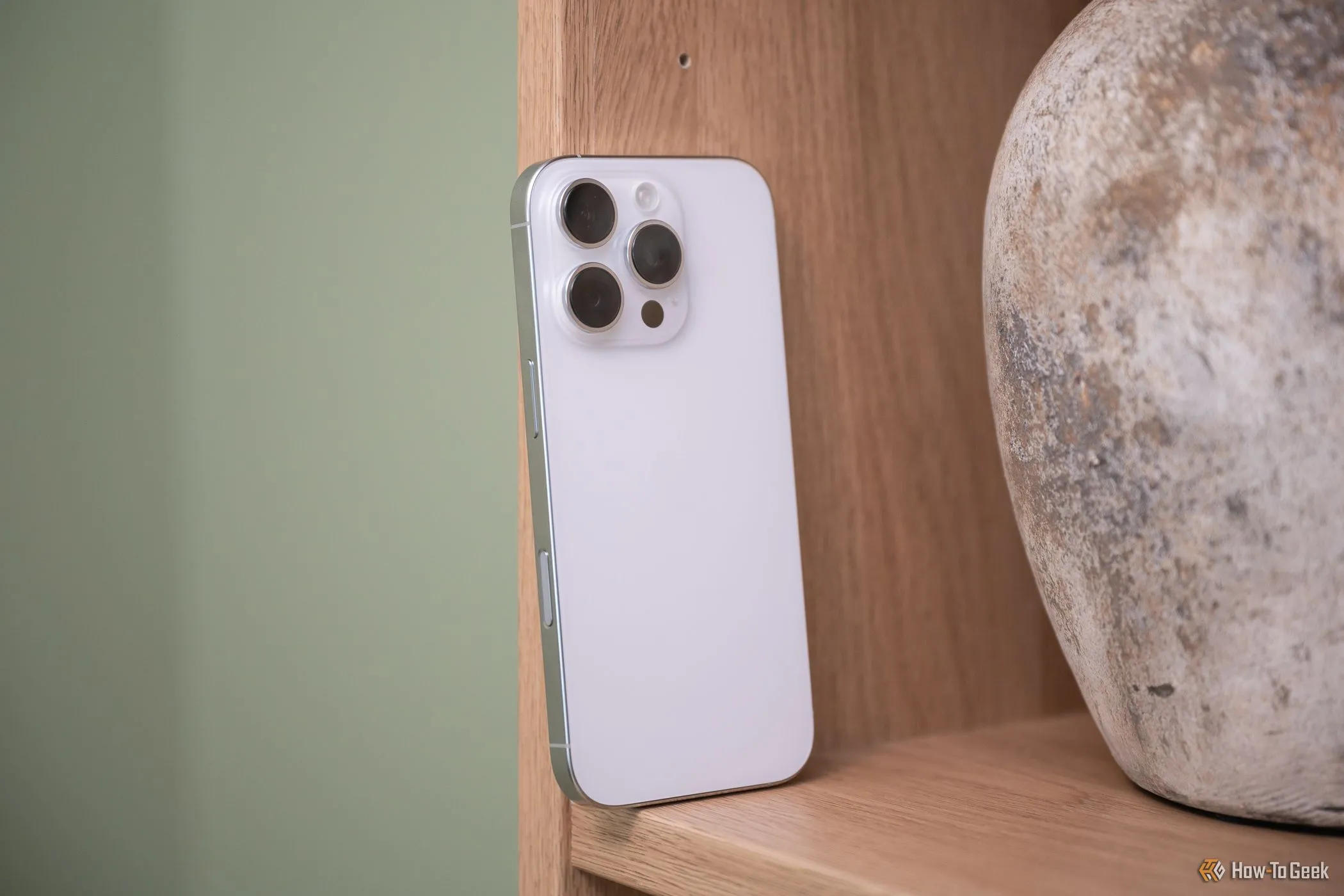 iPhone 16 Pro đặt trên giá sách, hiển thị nút điều khiển camera