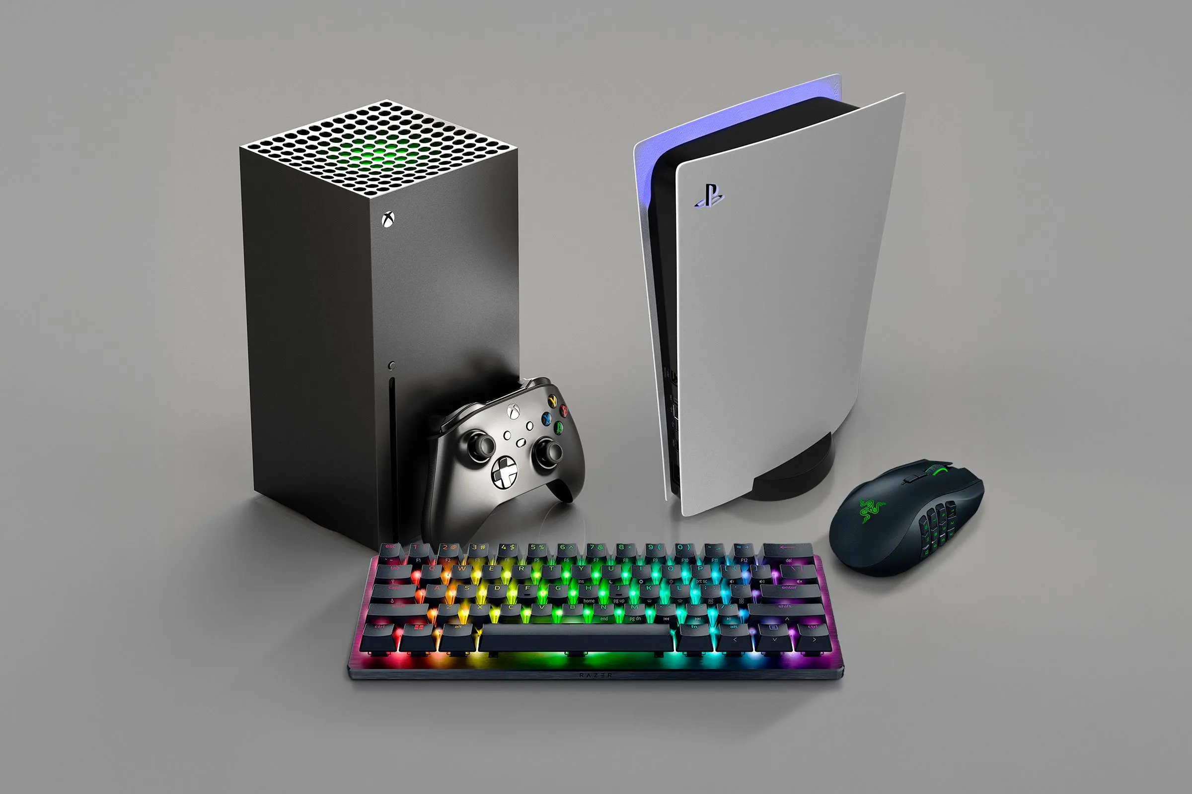 Máy chơi game Xbox và PlayStation đặt cạnh nhau cùng bàn phím chuột, đại diện cho các nền tảng game phổ biến với hệ thống thành tích.