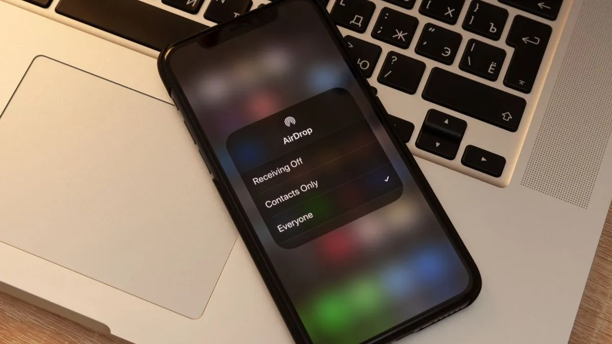 Một chiếc iPhone hiển thị lời nhắc AirDrop đặt trên MacBook, minh họa sự tiện lợi của hệ sinh thái Apple.