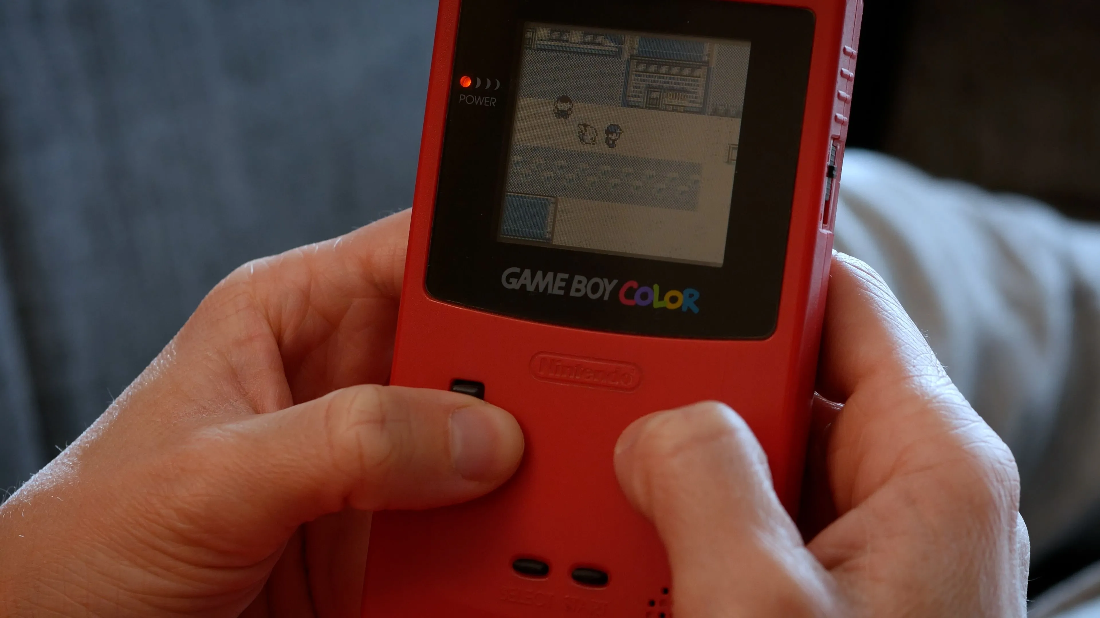 Người chơi game Pokemon trên hệ máy Game Boy Color, gợi nhớ kỷ niệm về game nhập vai Pokemon cổ điển.