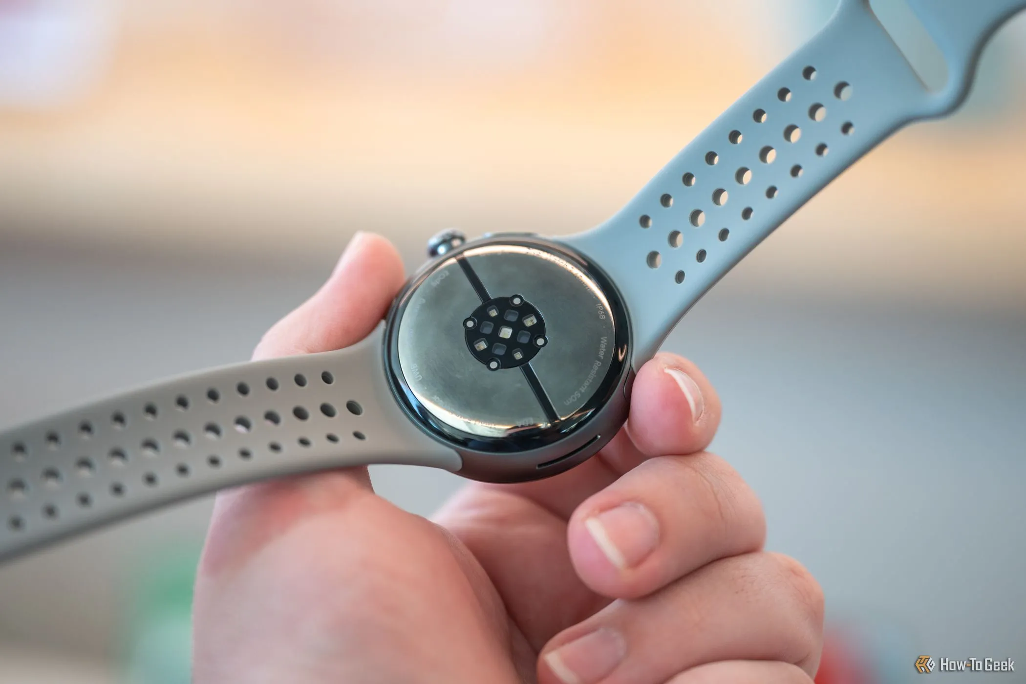 Người dùng cầm Google Pixel Watch 3, cho thấy các cảm biến ở mặt đáy