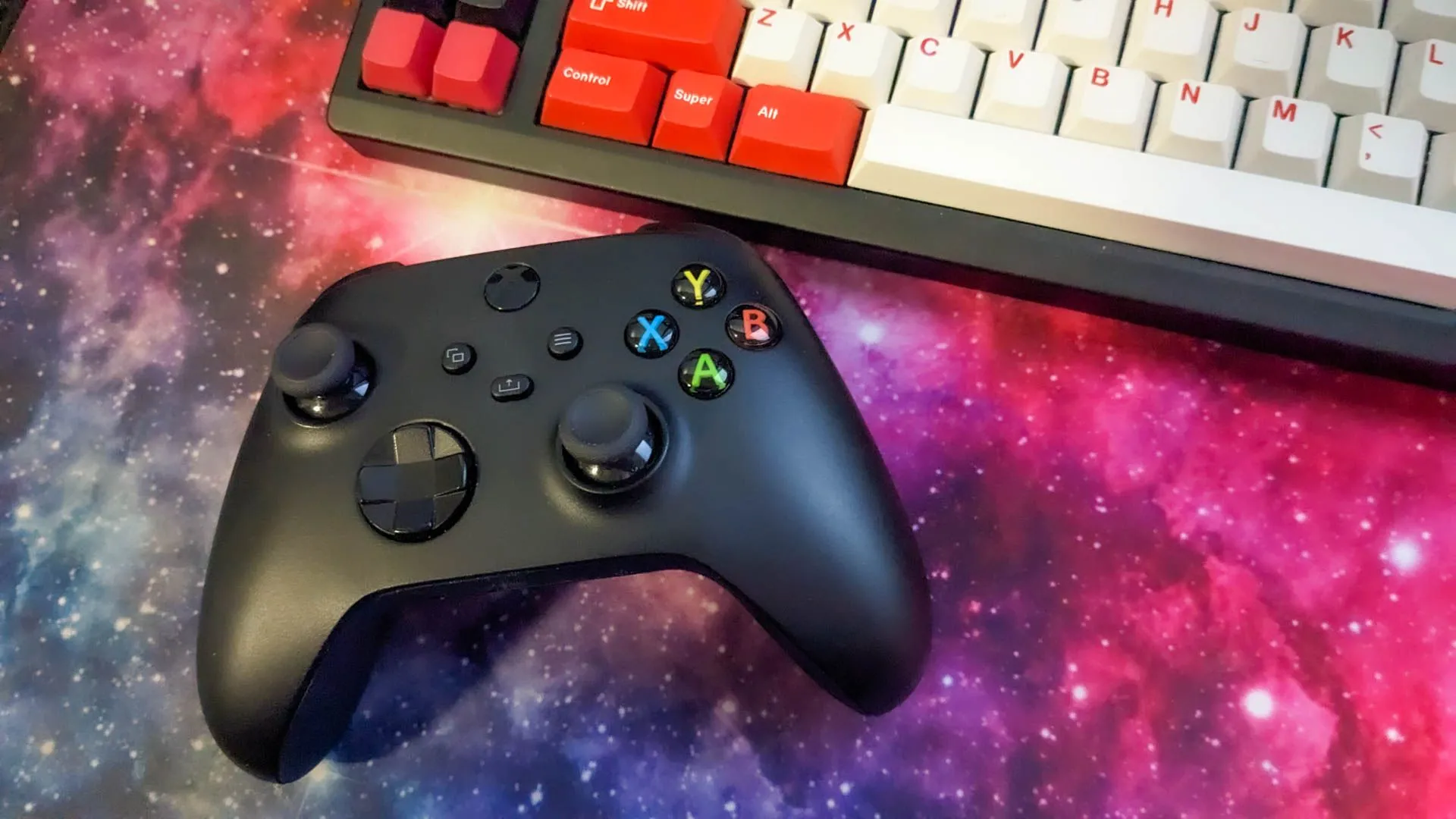 Tay cầm Xbox và bàn phím cơ trên bàn di chuột không gian