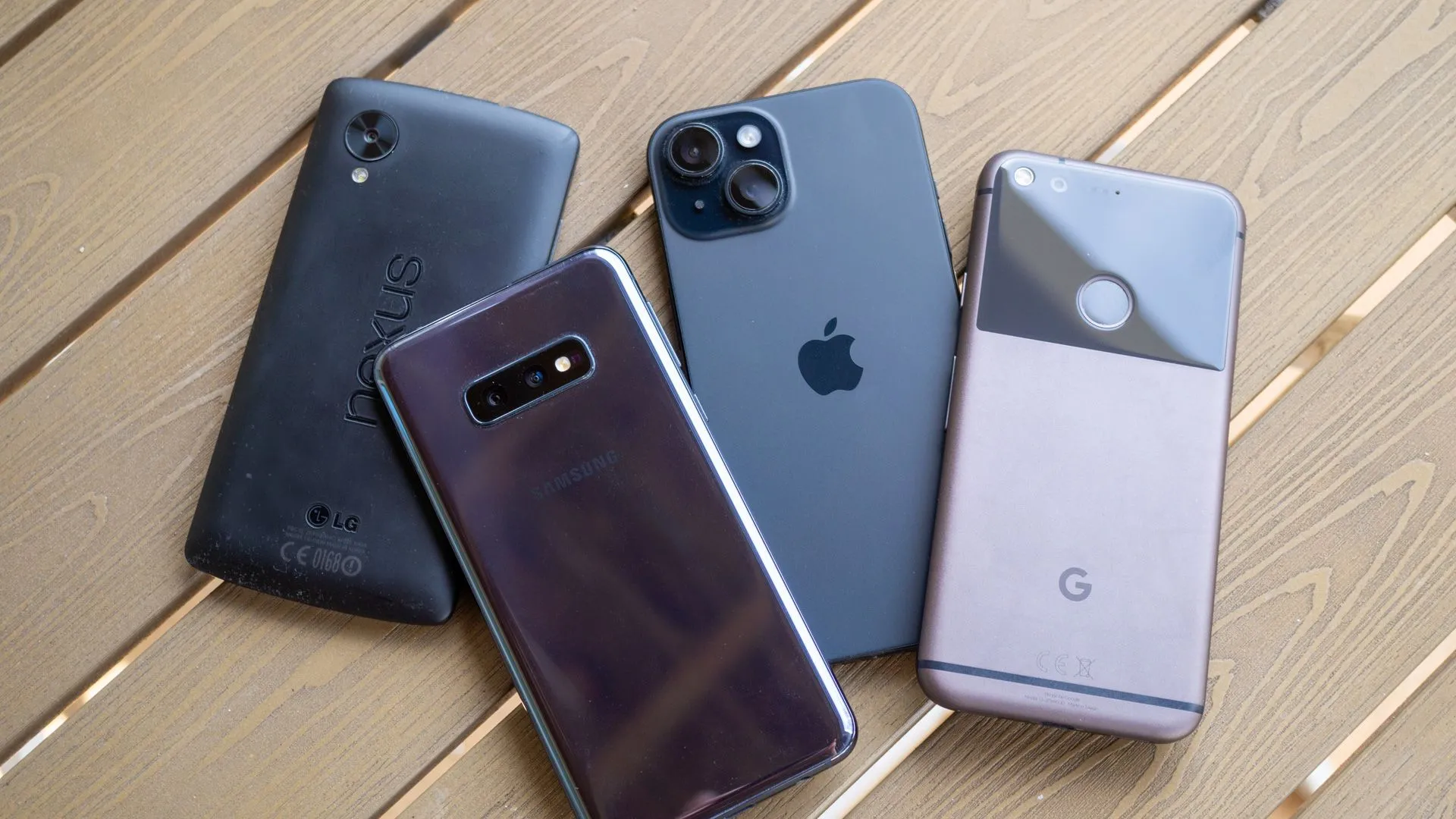 Bộ sưu tập các mẫu điện thoại cũ và mới từ Nexus 5, Galaxy S10e, iPhone 15 đến Google Pixel trên bàn.