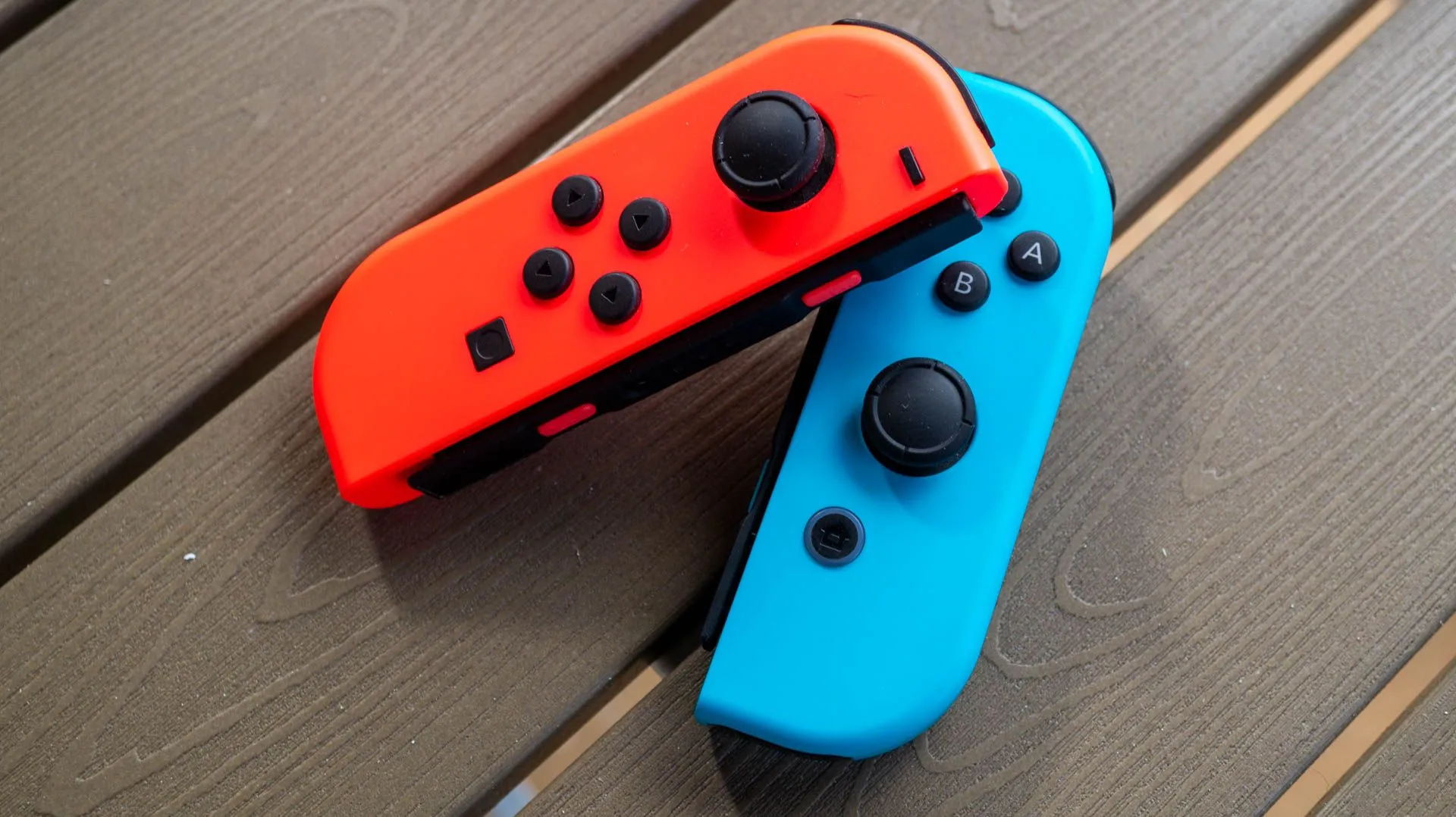 Cặp tay cầm Joy-Con màu xanh và đỏ của Nintendo Switch đặt trên bàn, thể hiện chi phí thay thế