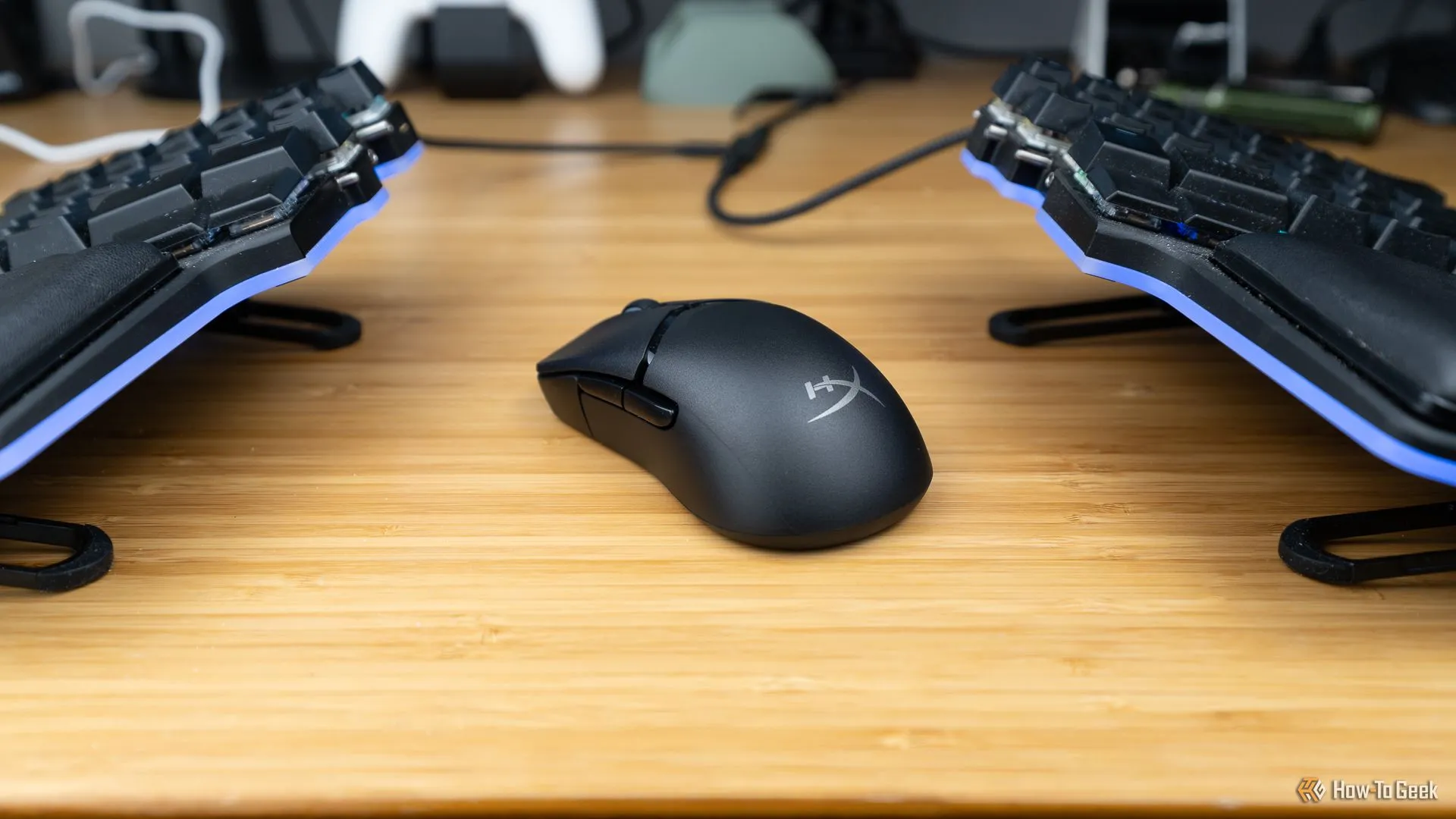 Chuột gaming HyperX Pulsefire Saga Pro đặt giữa hai nửa bàn phím cơ