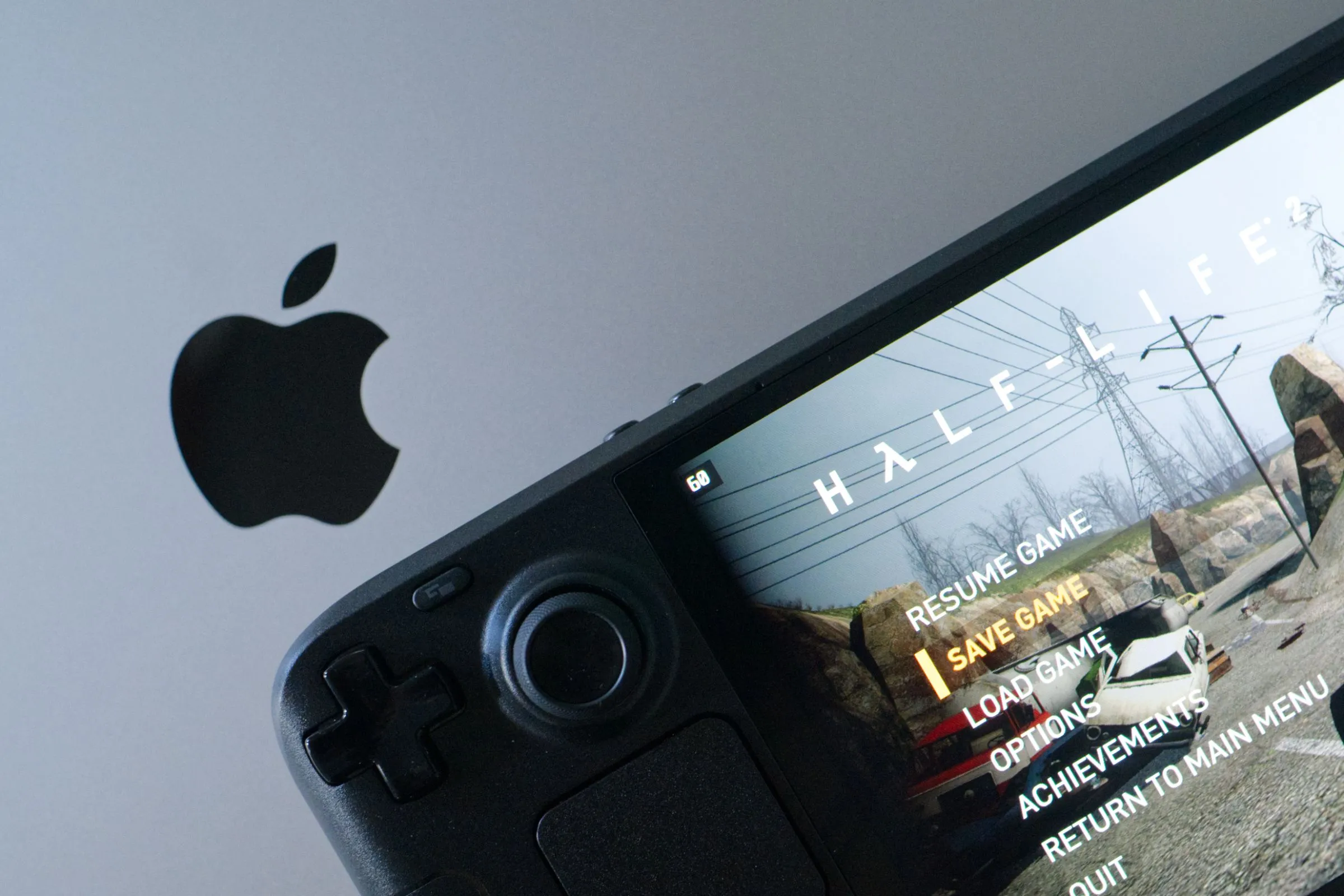 Game Half-Life 2 chạy trên Steam Deck OLED đặt cạnh MacBook Pro, cho thấy sự đa dạng của nền tảng chơi game di động và PC.