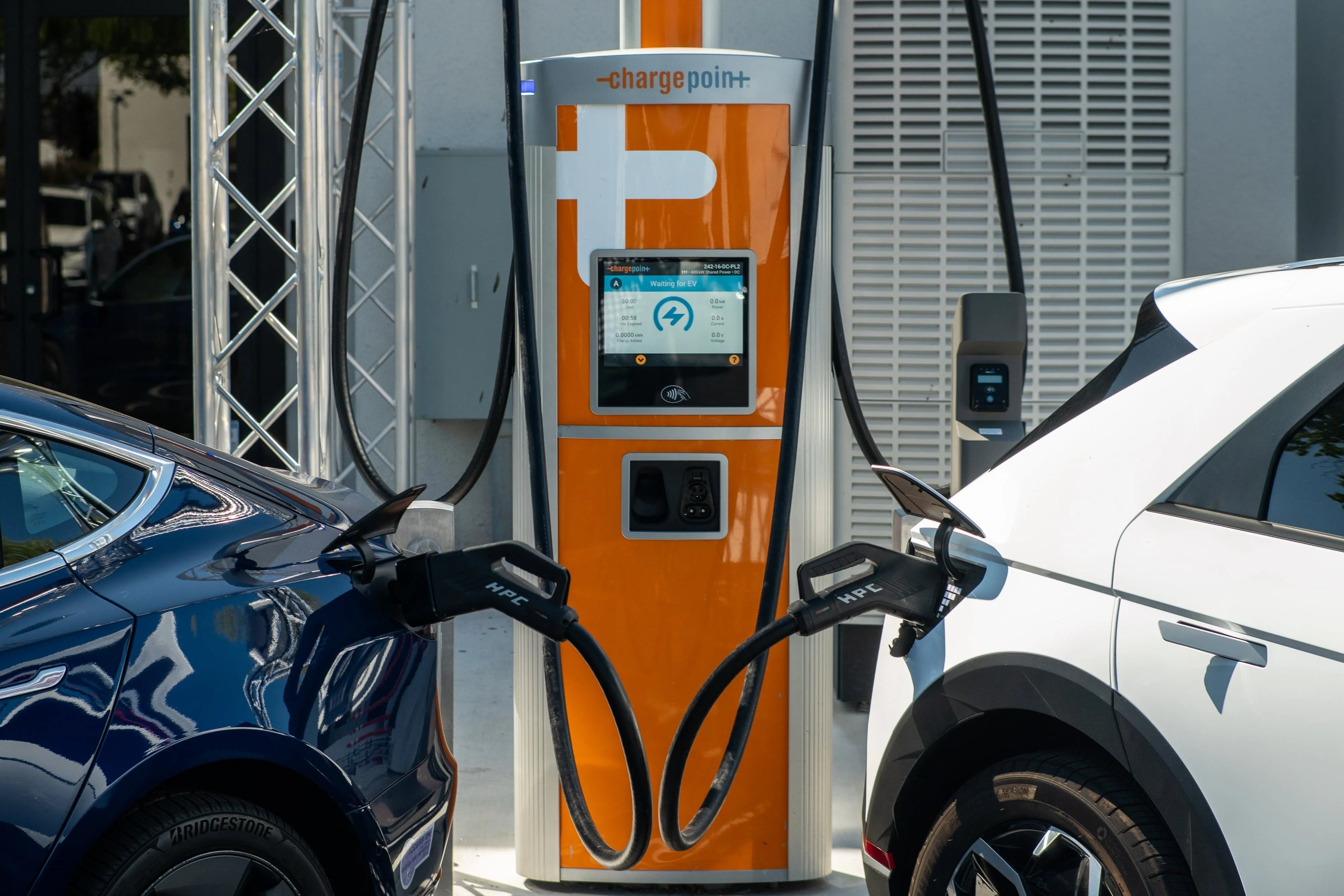 Hai chiếc xe điện đang sạc tại trạm sạc ChargePoint, với đầu nối Omniport và sạc nhanh DC.