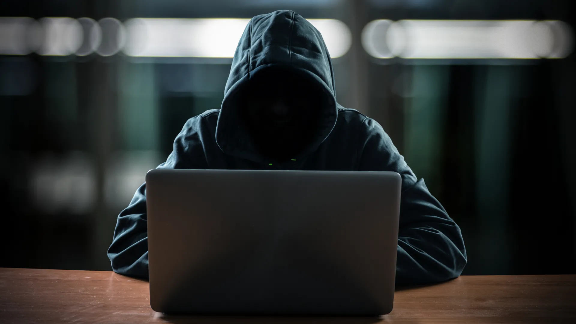Hình ảnh một hacker với khuôn mặt tối, ngồi trước máy tính, tượng trưng cho các mối đe dọa bảo mật và nguy cơ 'juice jacking' qua cổng sạc.