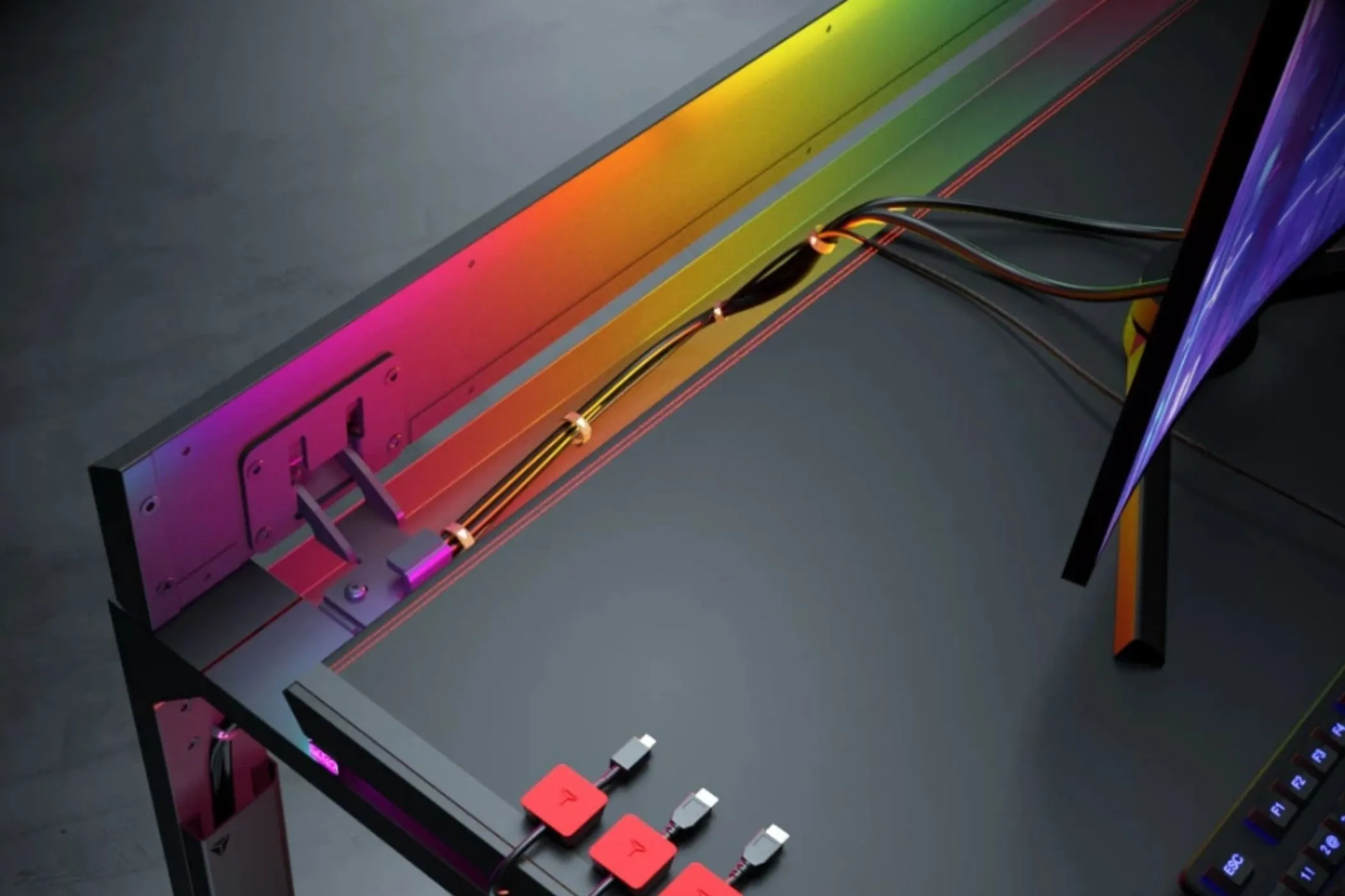 Hình ảnh quản lý dây cáp gọn gàng trên bàn làm việc Secretlab Magnus Pro với các sợi cáp và đèn RGB, minh họa giải pháp quản lý cáp hiệu quả cho hệ thống đa màn hình