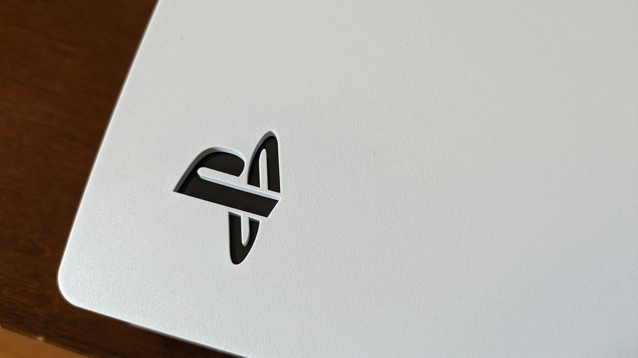 Logo PS5 màu trắng nổi bật trên nền console PlayStation 5 màu trắng, thể hiện thương hiệu đặc trưng của hệ máy