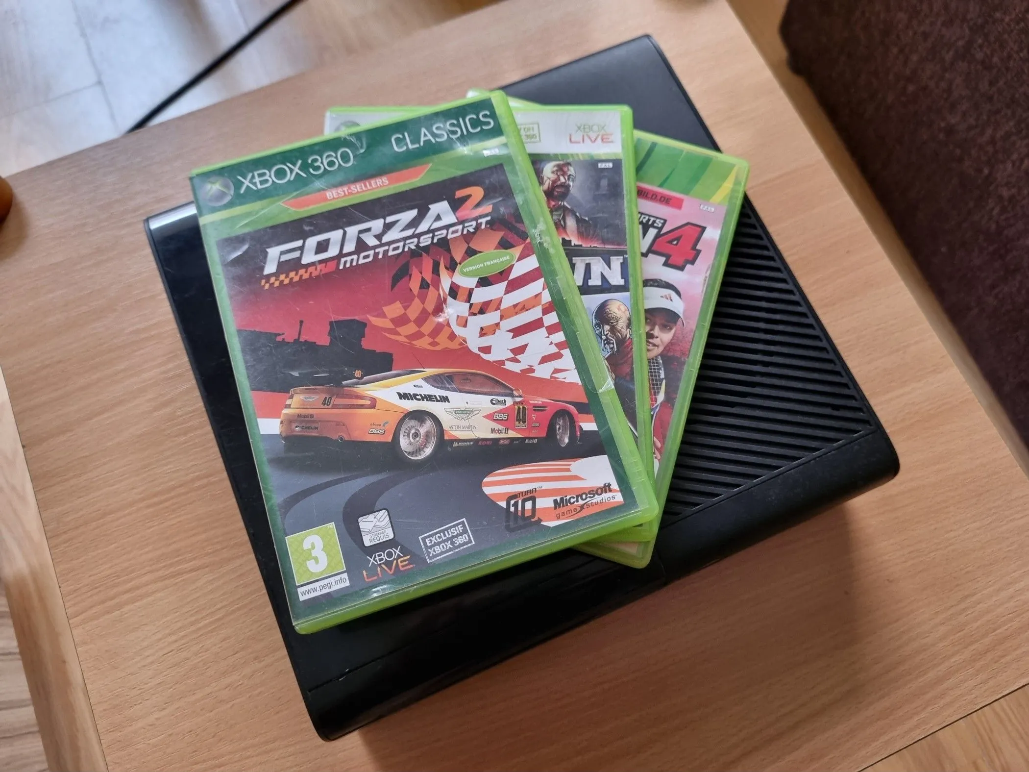 Máy console Xbox với nhiều hộp game đặt chồng lên nhau.