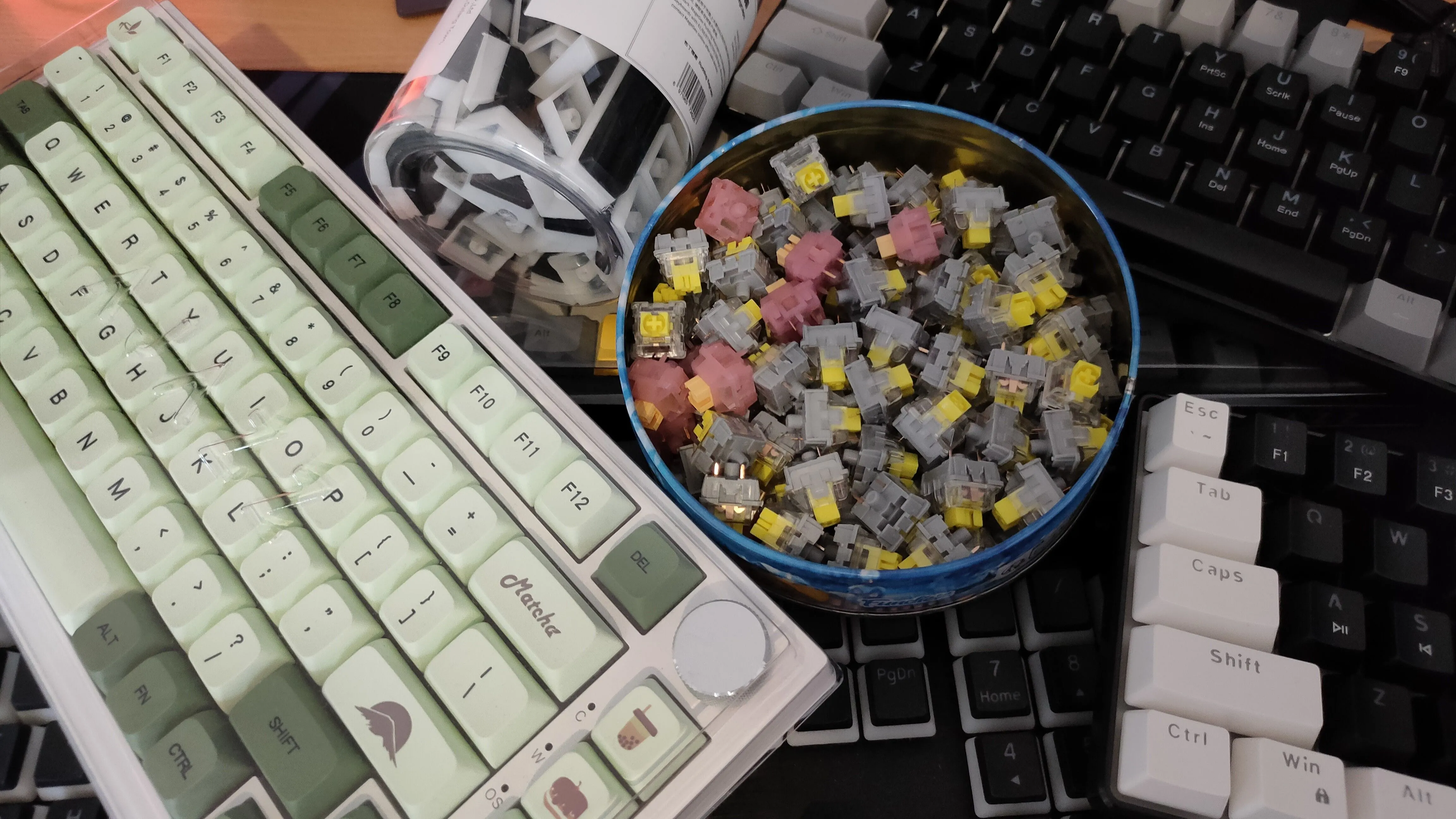 Một bộ sưu tập các bàn phím, switch và keycap của bàn phím cơ trên bàn, thể hiện sự đa dạng của linh kiện.