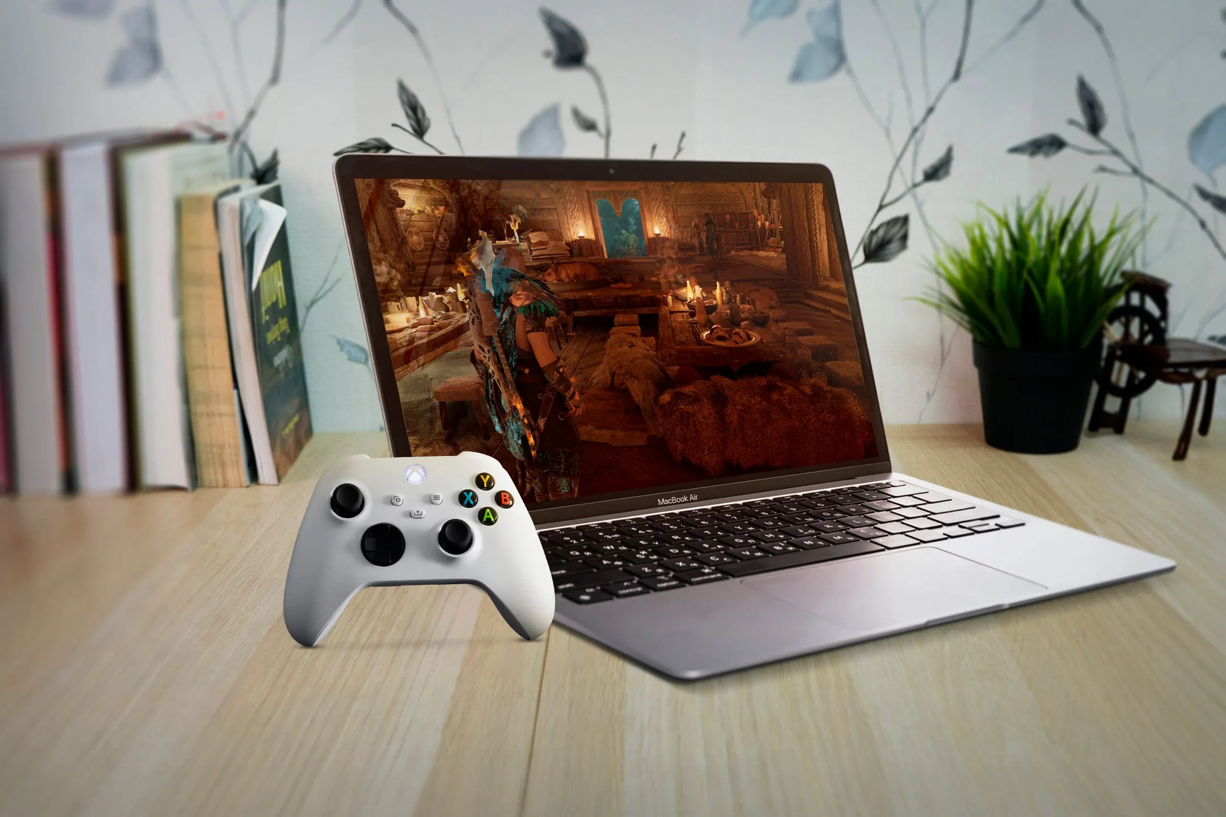 Một chiếc MacBook Air đặt dưới bàn gỗ, hiển thị game cùng tay cầm Xbox, tượng trưng cho tiềm năng và các giải pháp chơi game trên nền tảng macOS.
