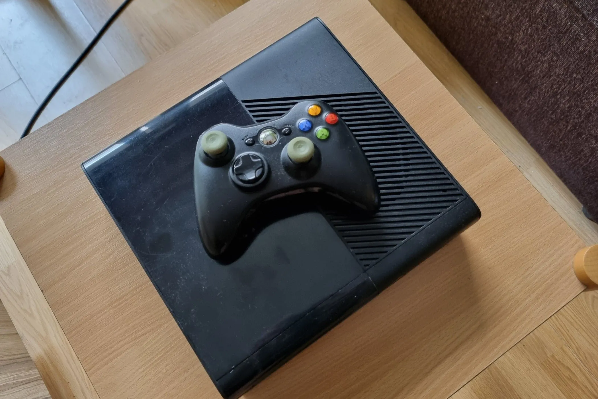 Một chiếc máy Xbox 360 đã qua sử dụng cùng tay cầm đặt phía trên.