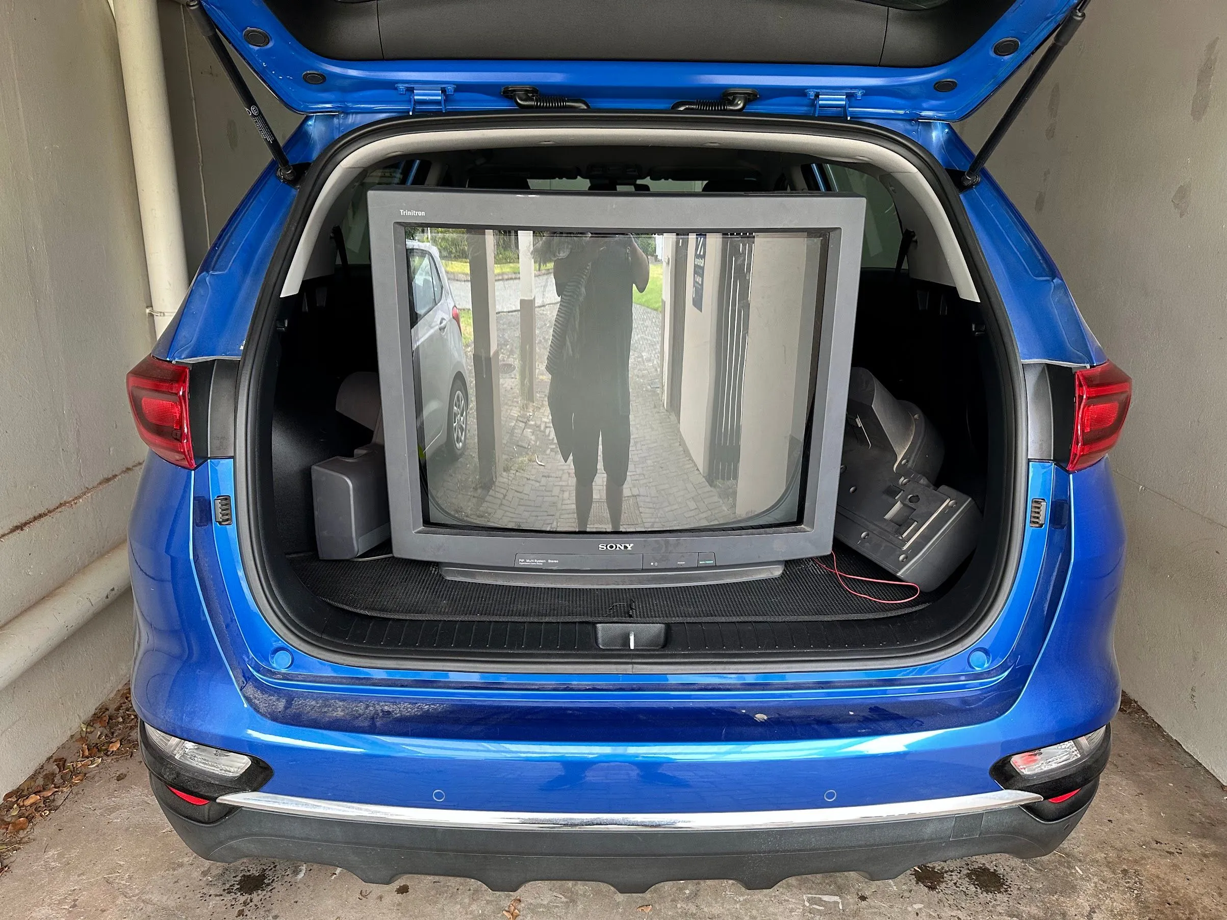 Một chiếc TV Sony CRT cồng kềnh được đặt trong cốp xe KIA Sportage, minh họa sự khó khăn khi vận chuyển các màn hình TV cổ điển lớn.