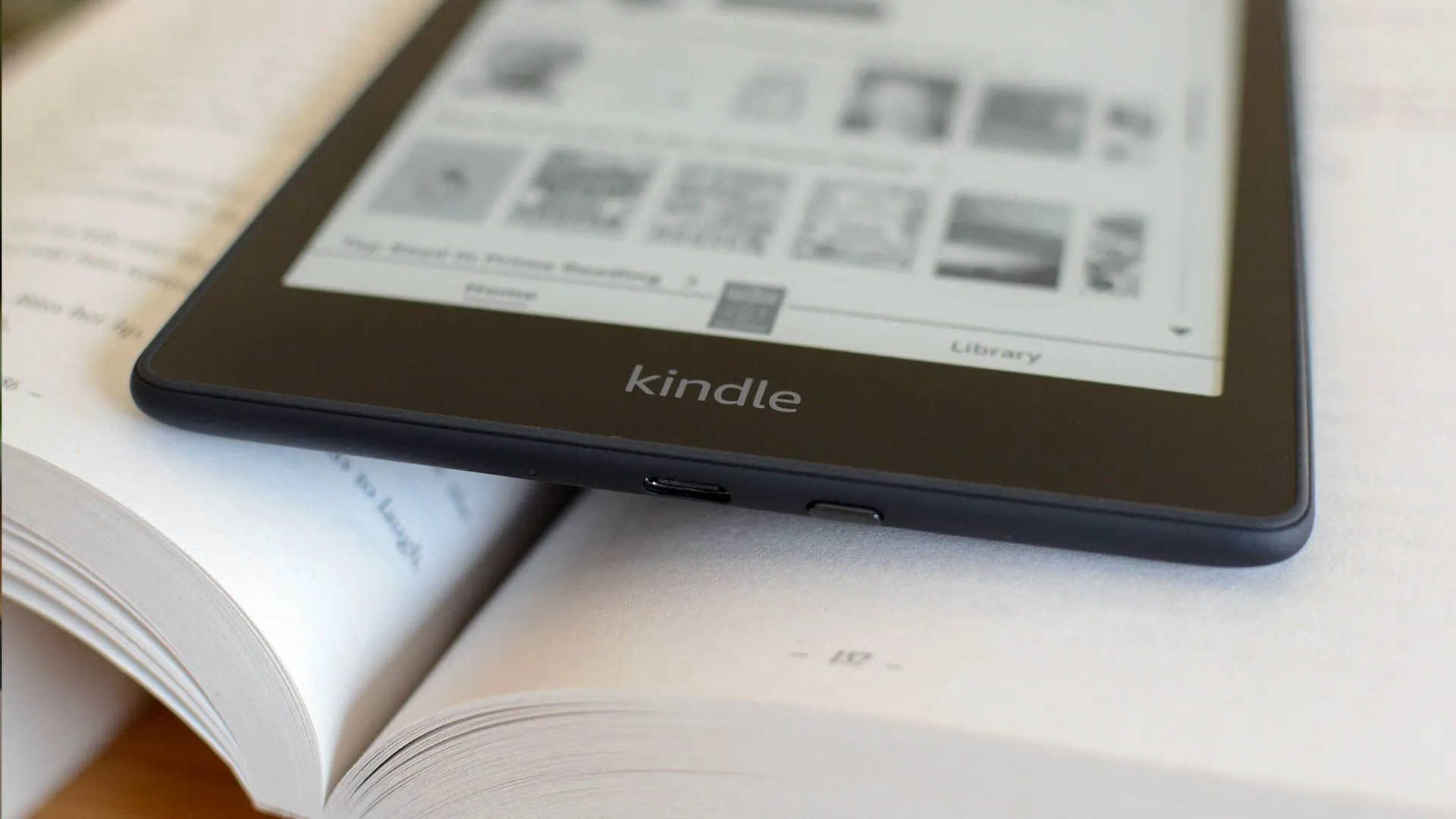 Một máy đọc sách Kindle đặt trên một cuốn sách giấy.