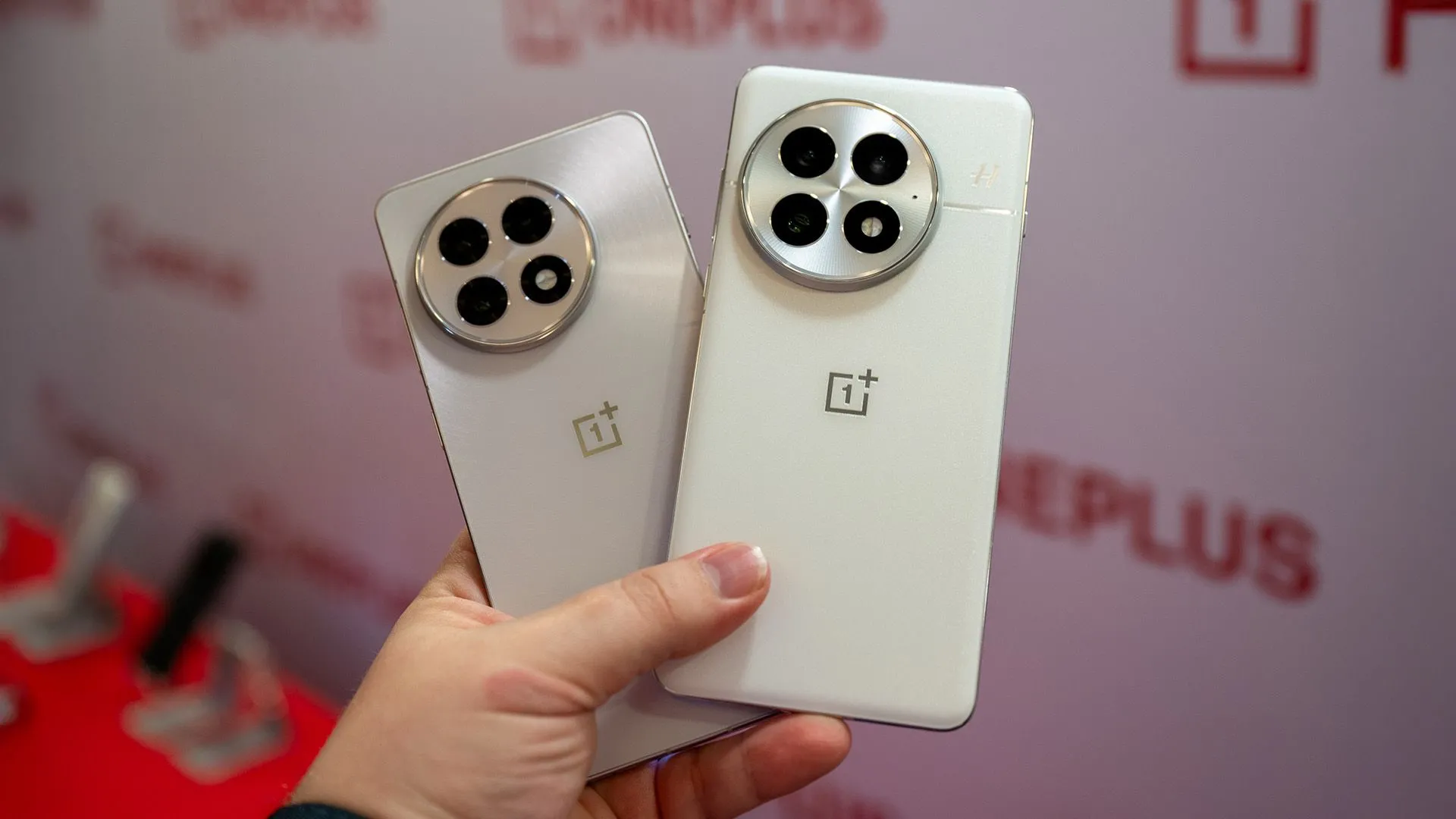Người dùng cầm hai chiếc điện thoại OnePlus 13 và OnePlus 13R màu trắng