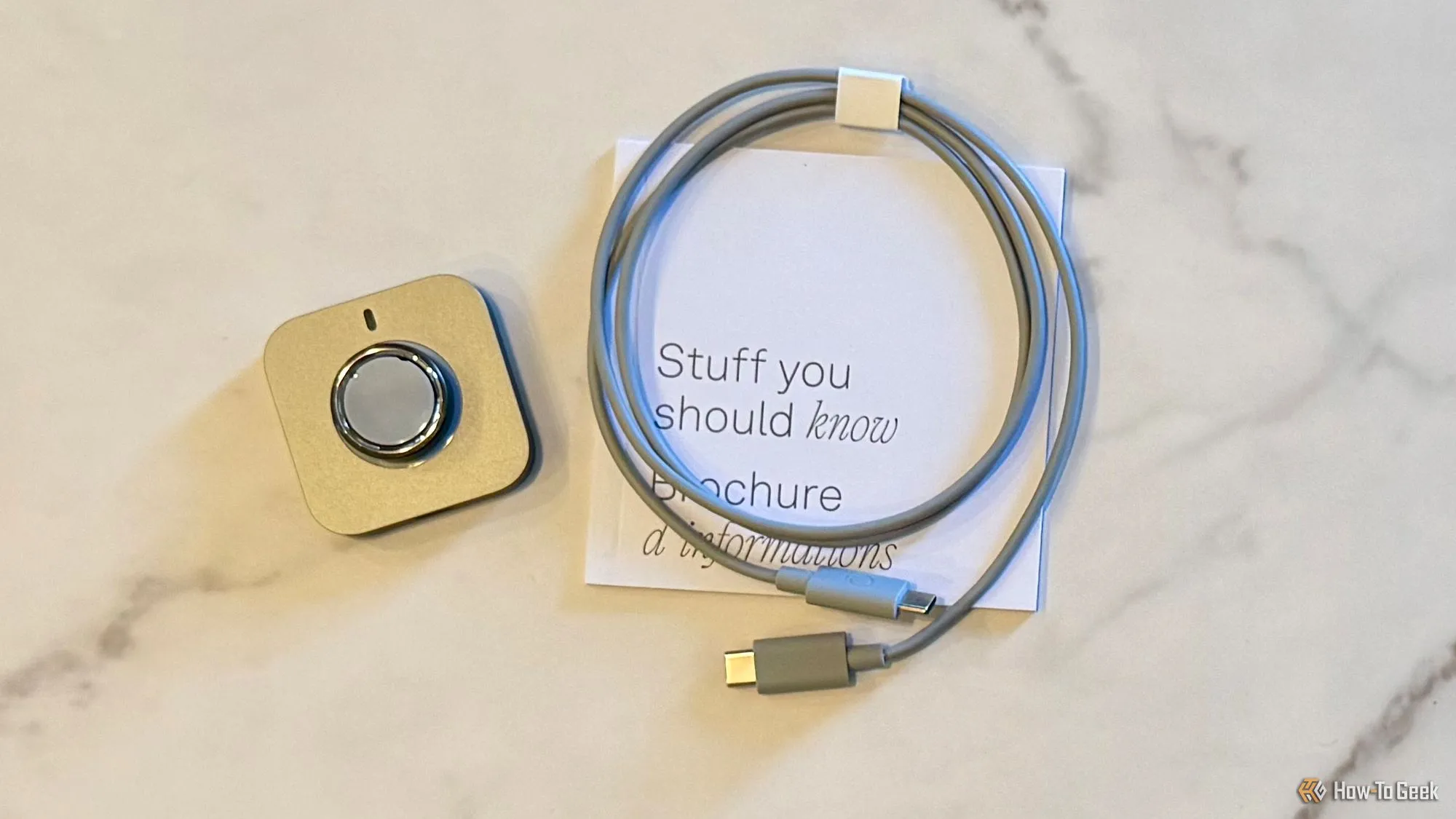 Trọn bộ sản phẩm Oura Ring 4 bao gồm nhẫn, cáp sạc USB-C và đế sạc, cùng tài liệu hướng dẫn.