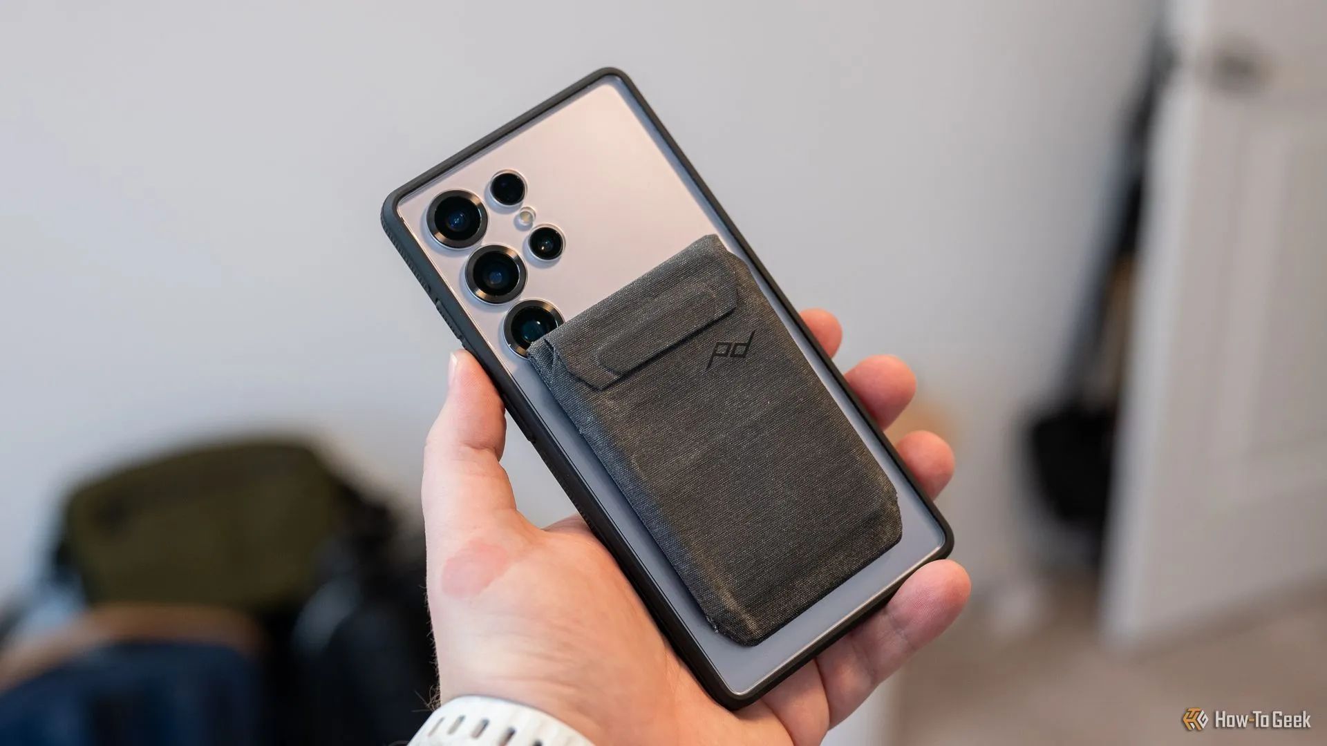Ví Peak Design Mobile gắn vào ốp lưng dbrand Ghost 2.0 trên Samsung Galaxy S25 Ultra, che một phần camera