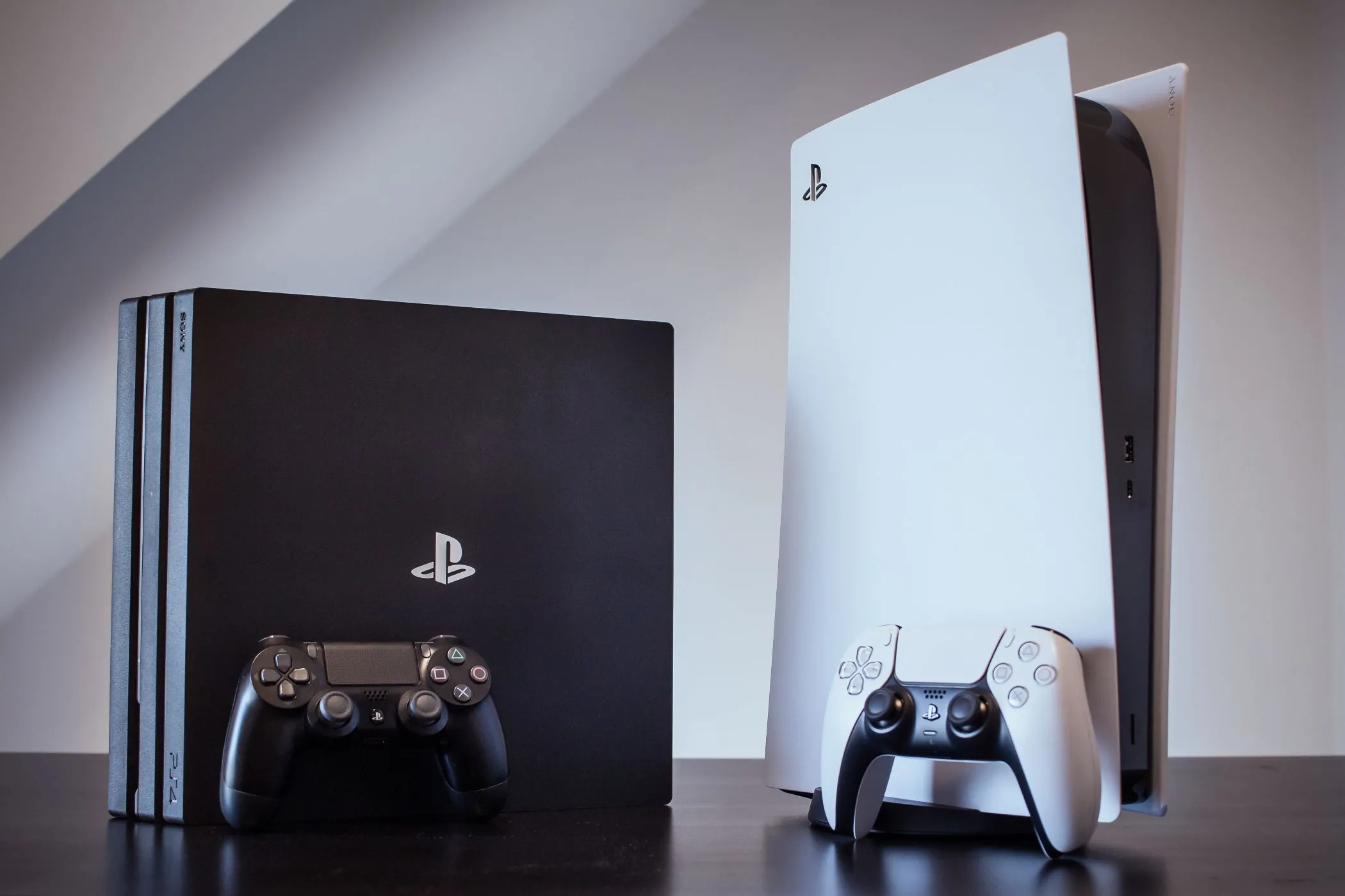 Console PS4 Pro và PS5 đặt cạnh nhau, thể hiện sự khác biệt tinh tế về đồ họa giữa thế hệ console thứ 8 và thứ 9.
