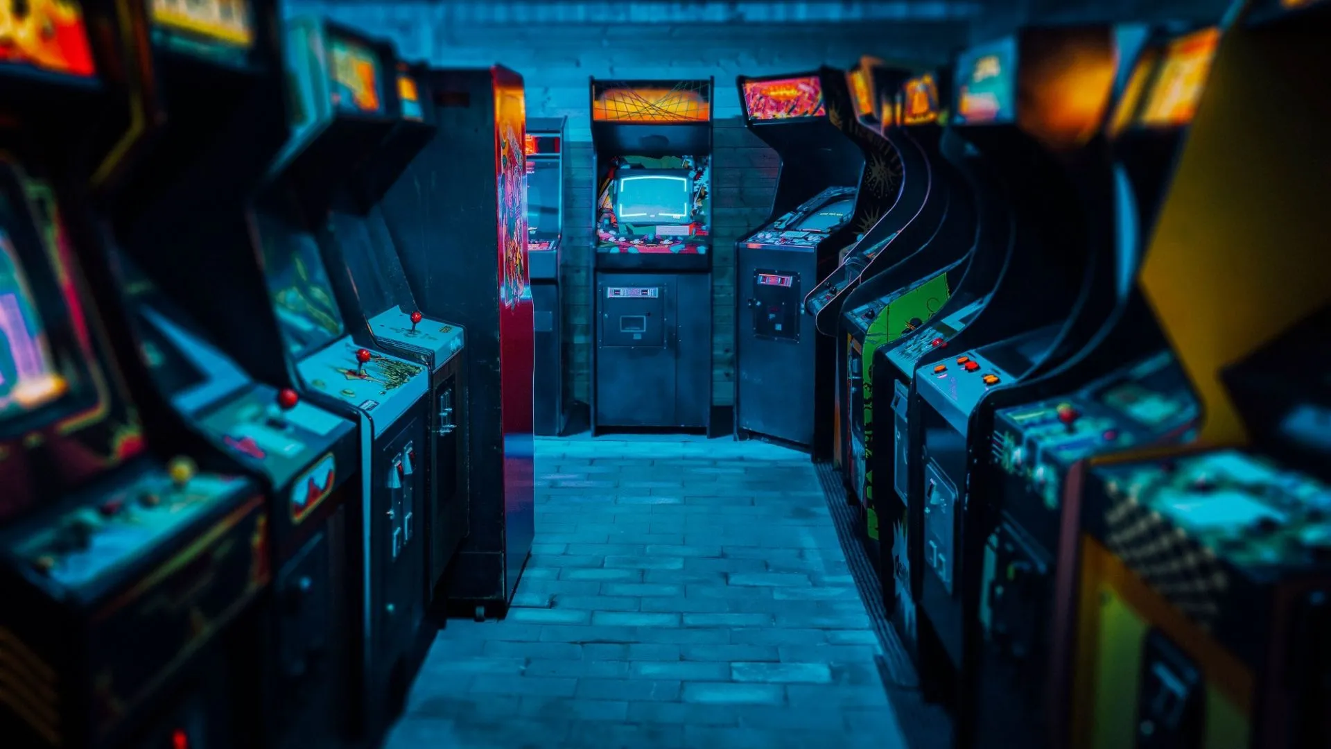 Dãy máy game thùng cổ điển trong một phòng tối, tái hiện không gian arcade truyền thống