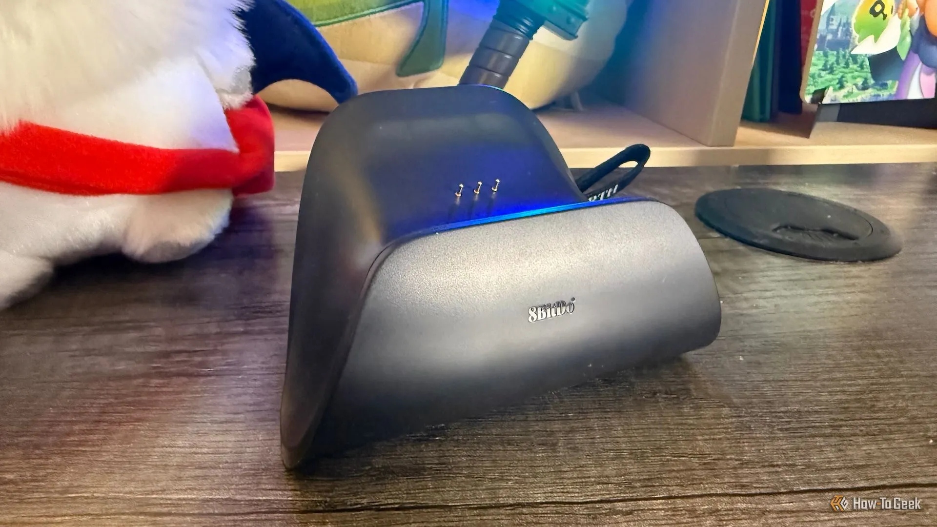Dock sạc nhỏ gọn của tay cầm 8BitDo Ultimate 2.4G trên mặt bàn, thể hiện tính tiện lợi khi sạc