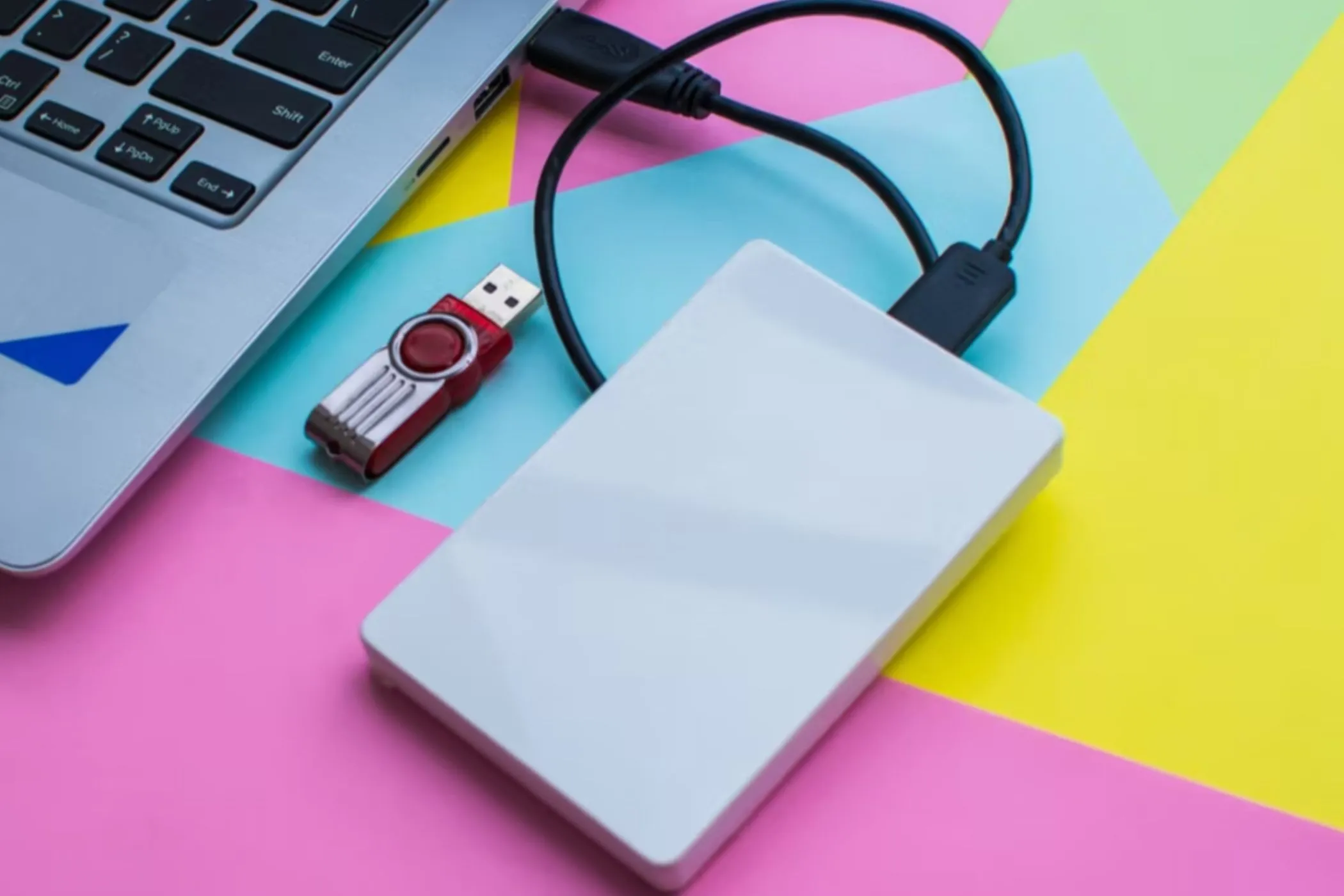 Ổ đĩa flash USB và ổ cứng gắn ngoài (external drive) được kết nối với laptop, phục vụ việc chuyển nhạc từ CD