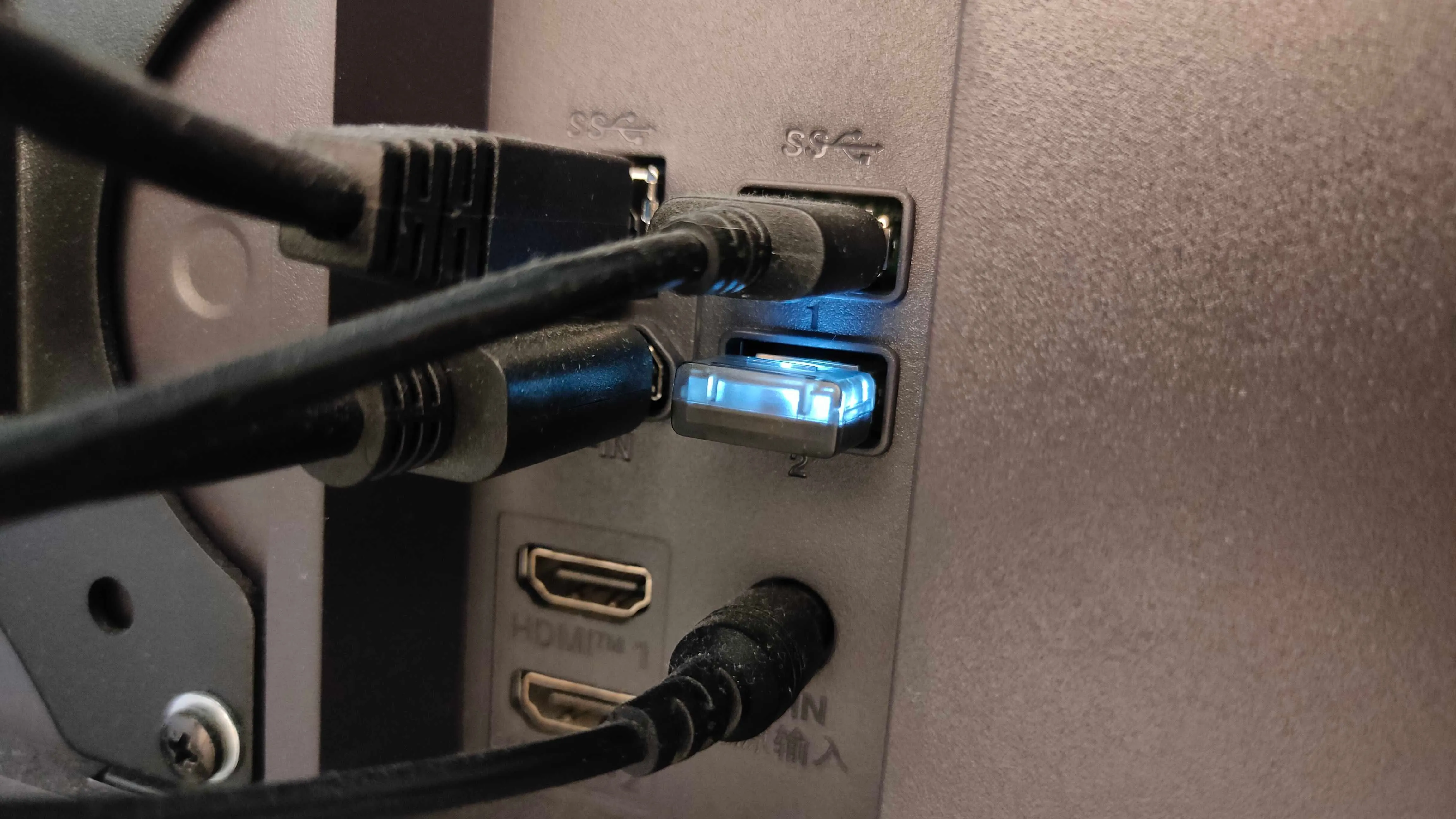 Dongle không dây 2.4GHz cắm vào cổng USB trên màn hình, giúp kết nối các thiết bị ngoại vi không dây ổn định hơn