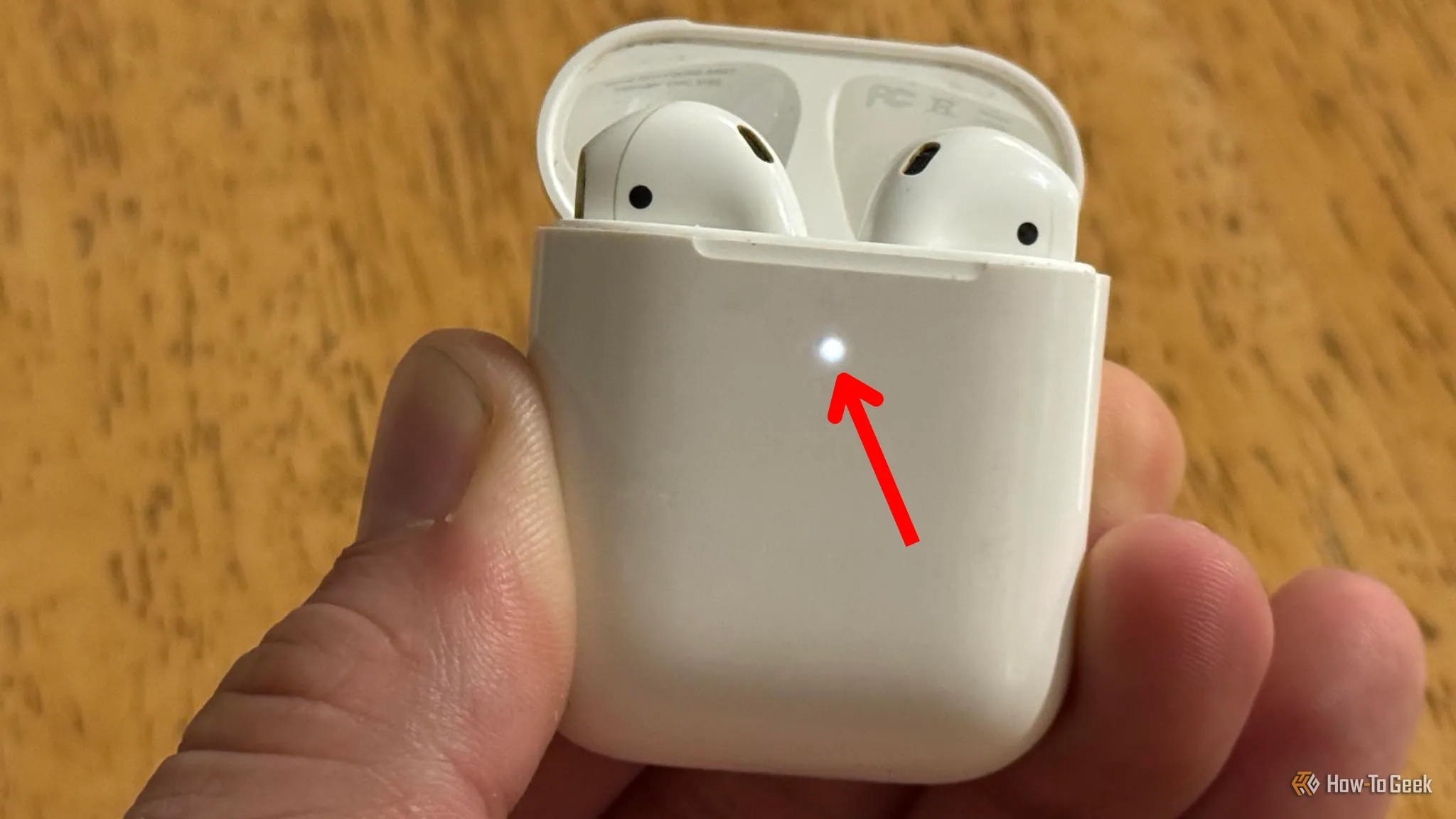 Hộp sạc Apple AirPods đang mở, đèn báo trạng thái nhấp nhấp nháy màu trắng, cho biết AirPods sẵn sàng ghép nối