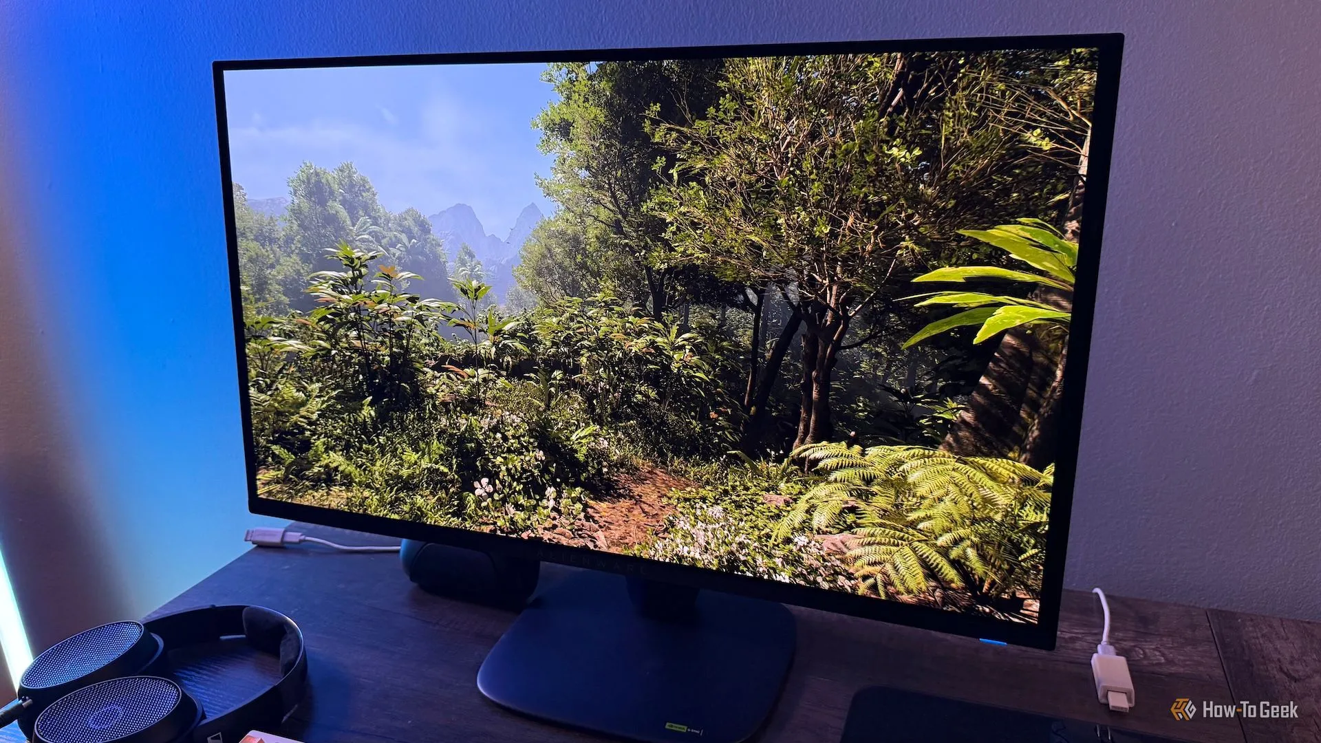Màn hình Alienware 27 4K QD-OLED (AW2725Q) hiển thị cảnh rừng rậm trong Indiana Jones, tạo thành một màn hình nghệ thuật số sống động.