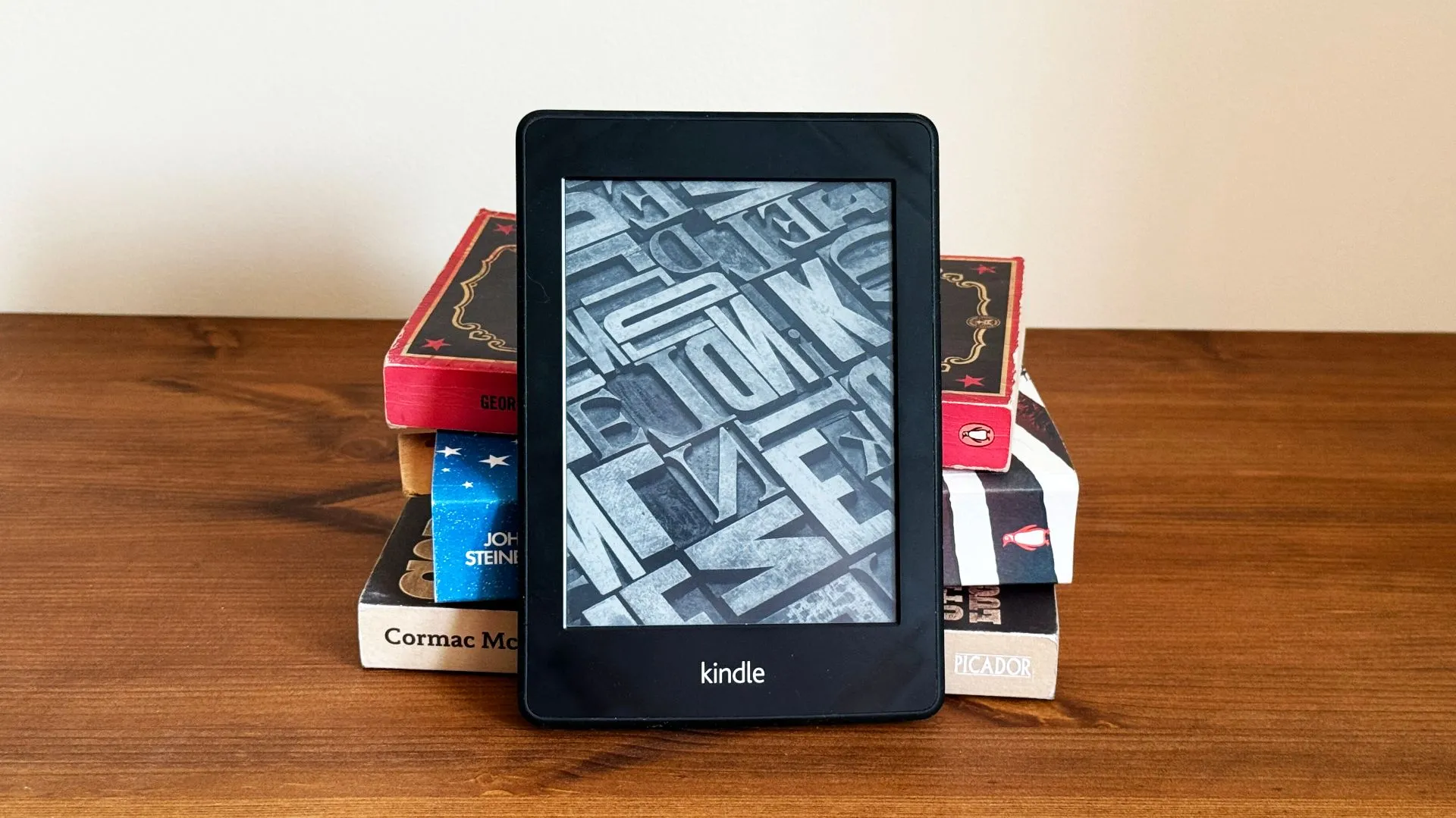 Máy đọc sách điện tử Kindle đặt trước chồng sách giấy
