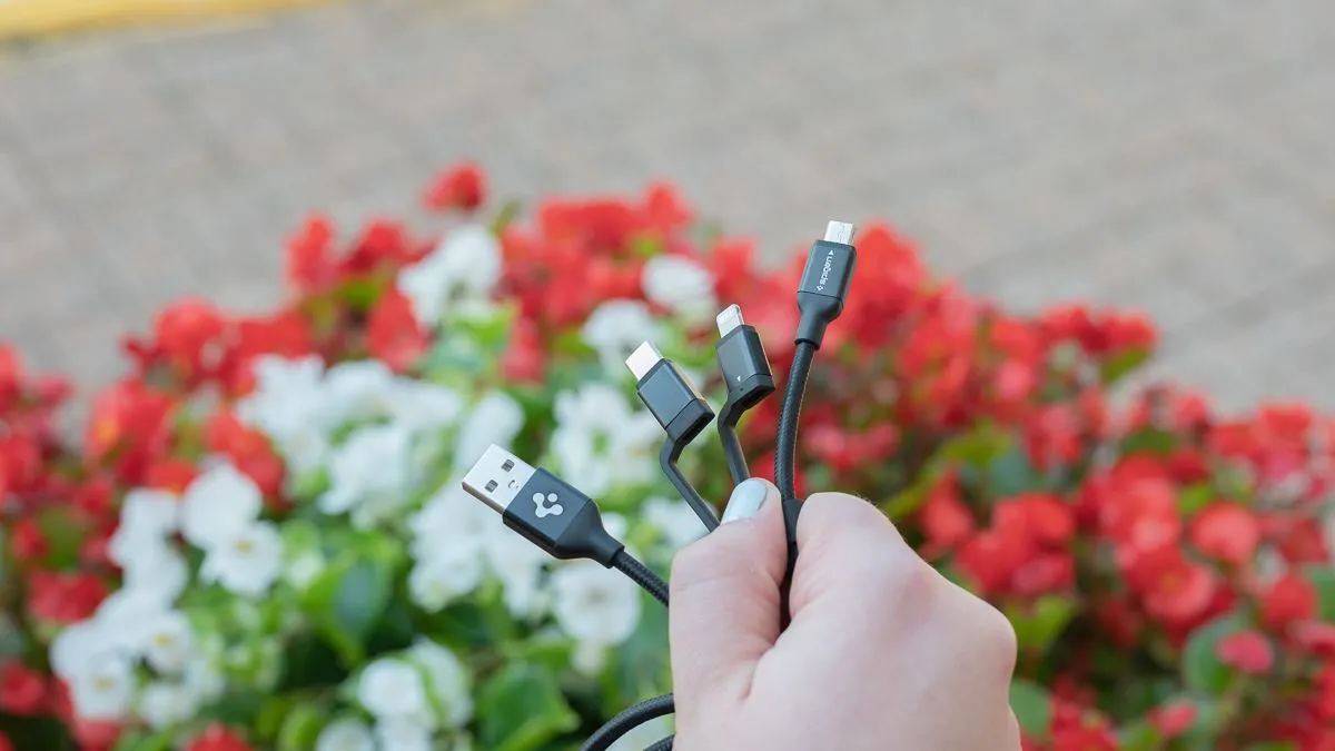 Một người đang cầm cáp sạc đa năng Spigen DuraSync 3-in-1, thể hiện sự tiện lợi.