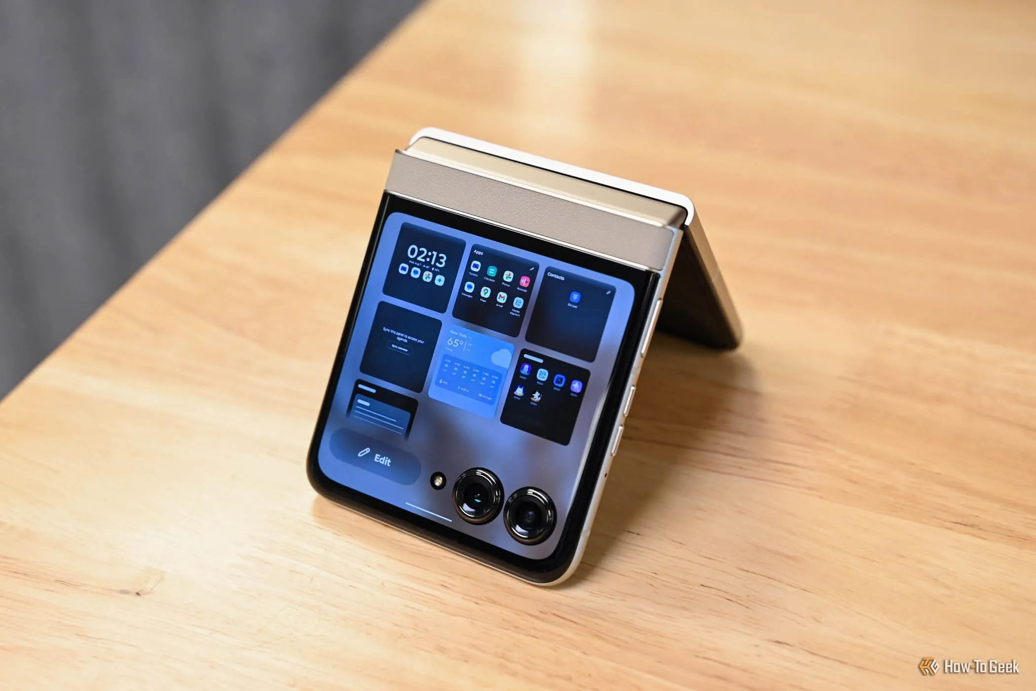 Motorola Razr đứng trên bàn gỗ, điện thoại gập thành hình chữ V ngược. 