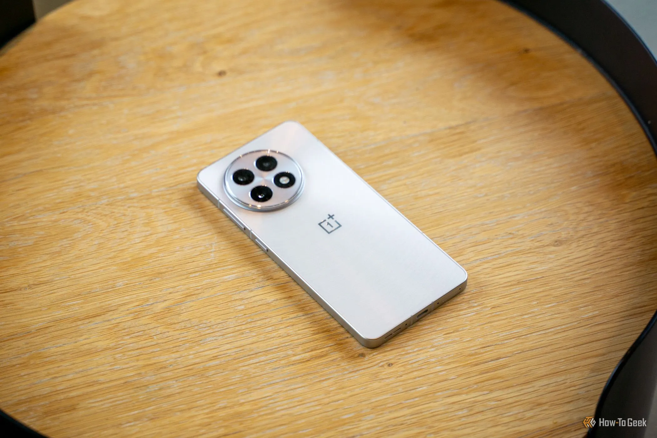 OnePlus 13R đặt úp mặt trên bàn gỗ, hiển thị cụm camera.